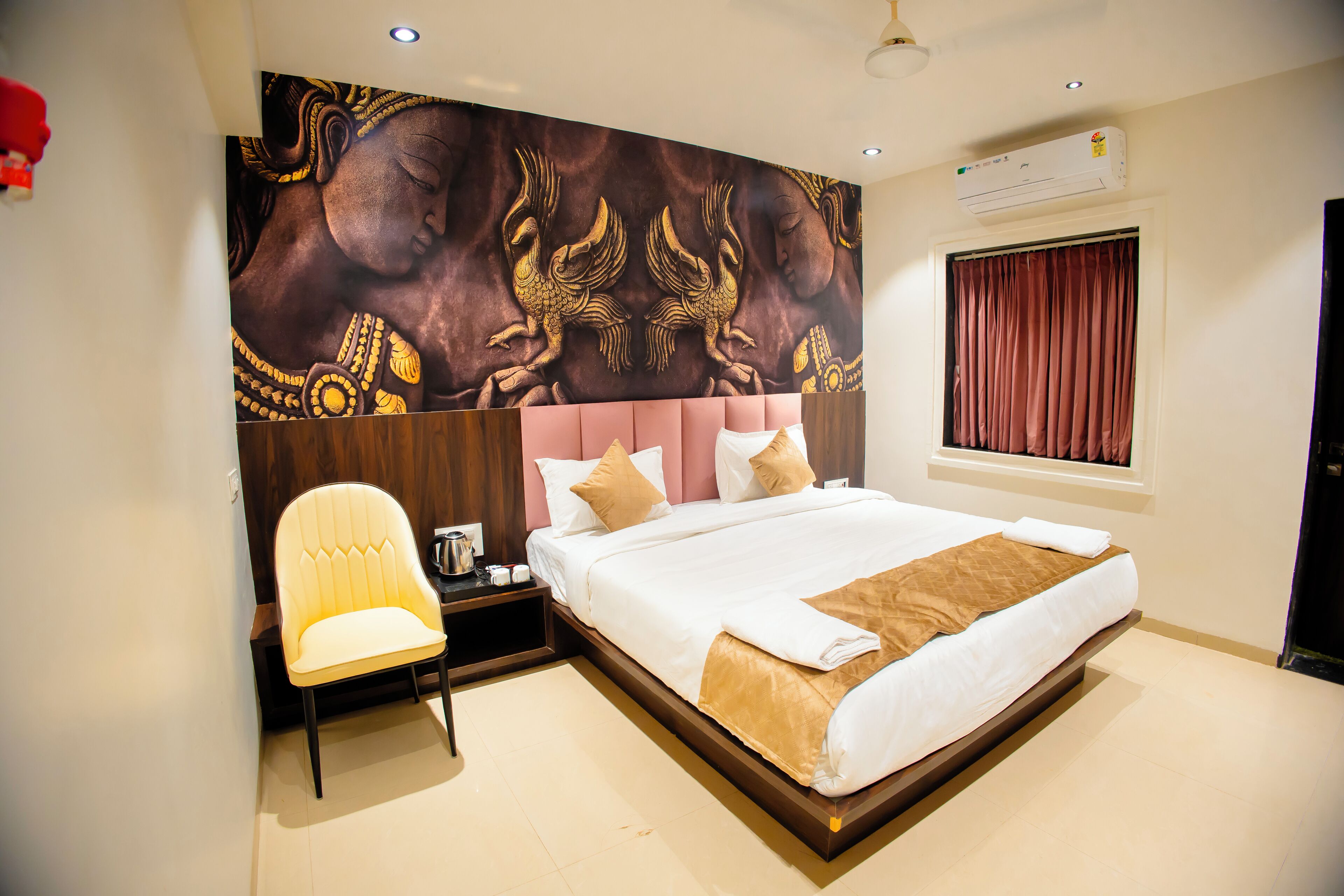 A hotel room with a large bed, a chair, a nightstand, and a wall mural.