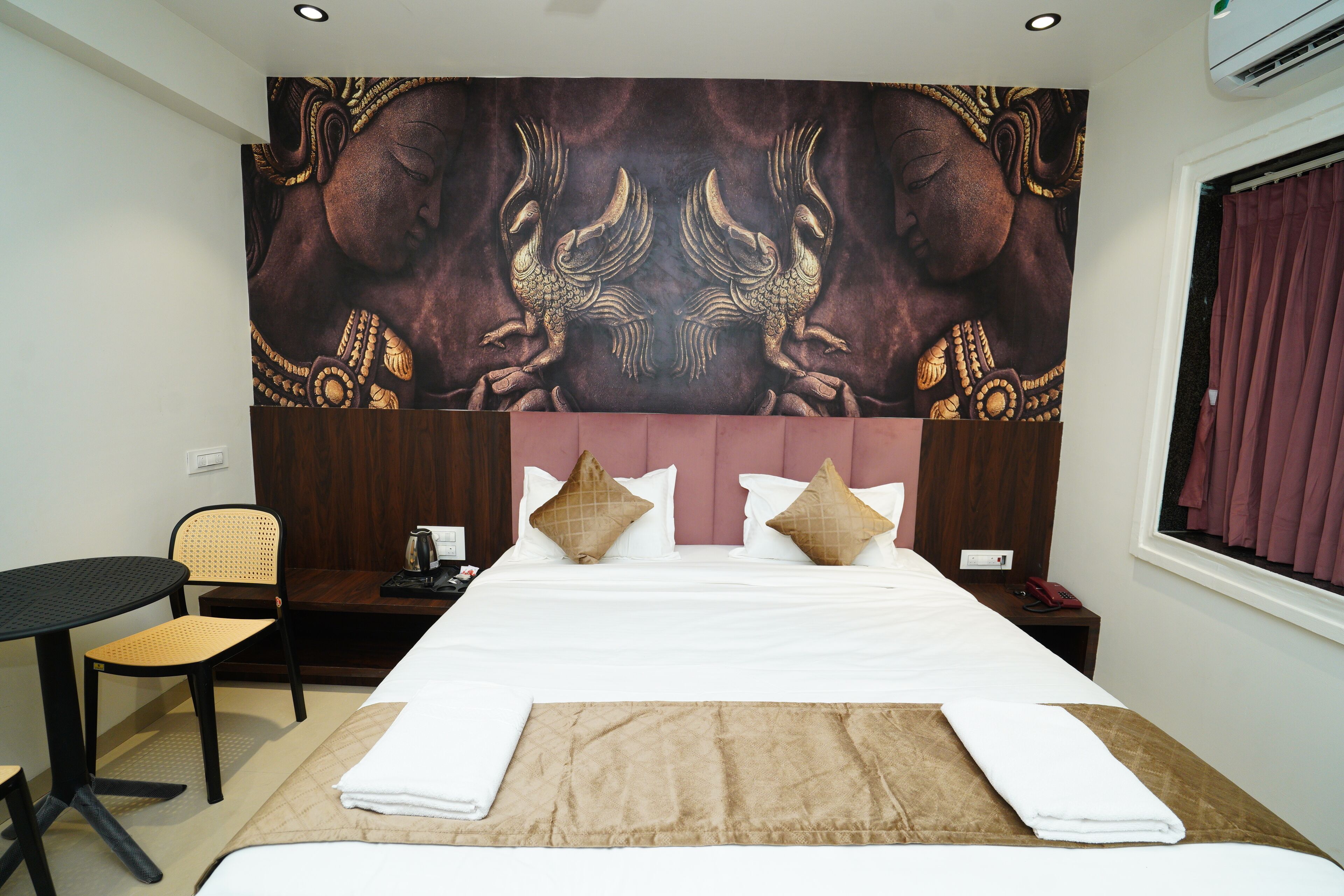 Een hotelkamer met een groot bed, een bureau, een stoel en een wandtapijt aan de muur.