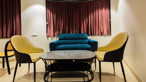 A modern living room with a blue sofa, yellow and black chairs, and a marble coffee table. - Kings Executive (Tuljapur)