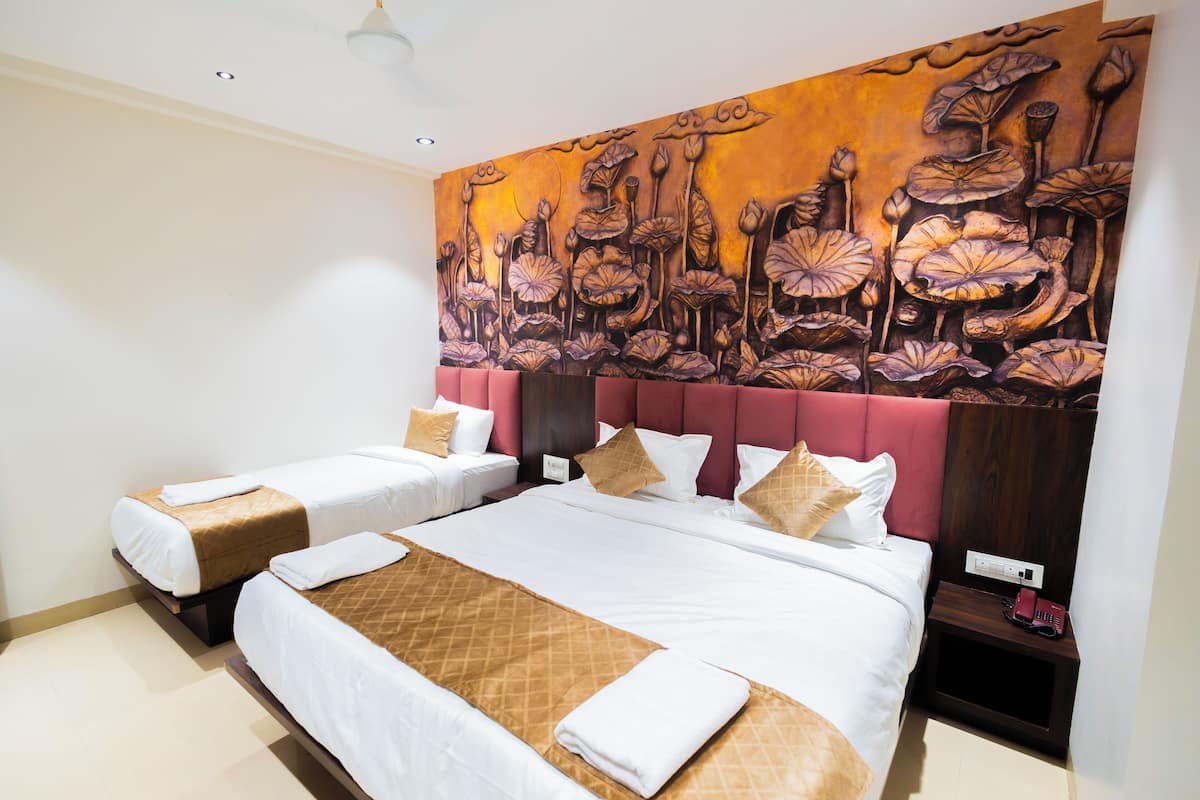 A hotel room with two beds, a large mural on the wall, and a nightstand with a phone.