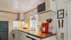 Cocina compacta con encimera de madera, microondas integrado, cafetera y lavavajillas.