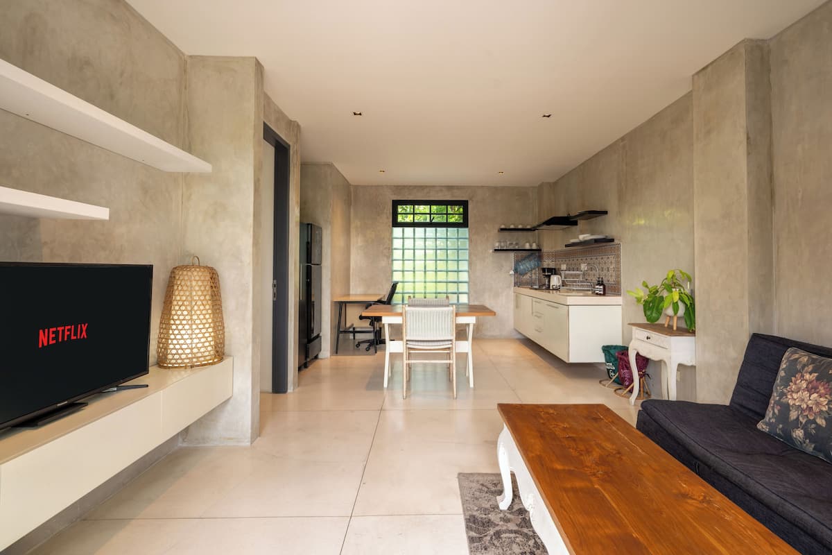 A modern living room with a TV, a wooden coffee table, a sofa, and a dining area with a table and chairs.