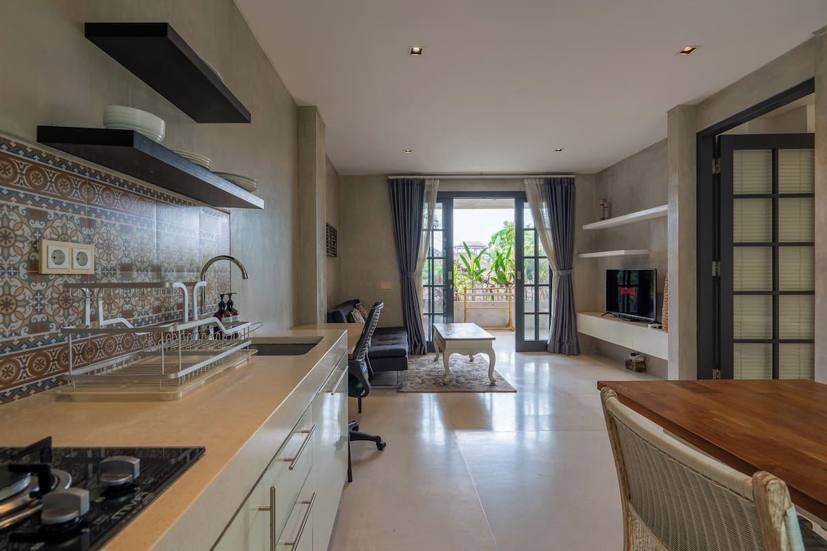 A modern kitchen with a central island, a dining area with a table and chairs, and a TV mounted on the wall.
