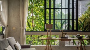 Ein Zimmer mit großem Fenster, Staffelei, Schreibtisch und einer Couch.