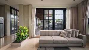 Ein modernes Wohnzimmer mit einem beigefarbenen Sofa, einer Topfpflanze und Blick auf den Balkon.