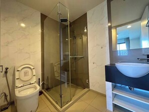A modern bathroom with a glass-enclosed shower, a toilet, and a sink with a dark countertop.