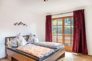 Een slaapkamer met een bed, een raam met gordijnen, een houten hoofdbord en een muur met silhouet van een berg.