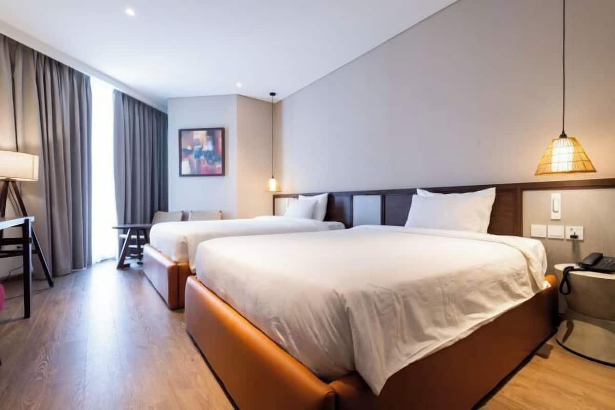 Een hotelkamer met twee bedden, een bureau, een stoel en een lamp.