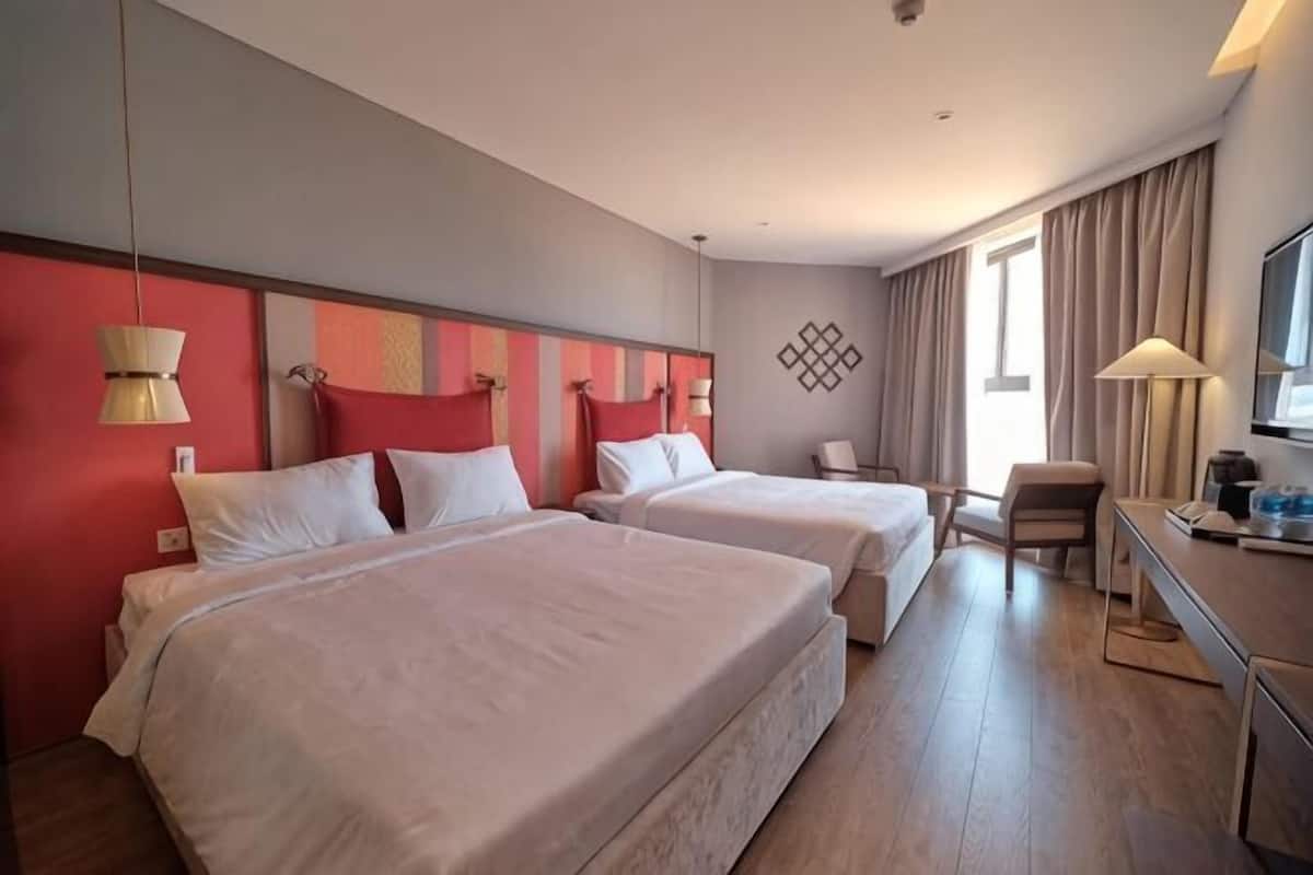 Een hotelkamer met twee bedden, een bureau, een stoel en een televisie.