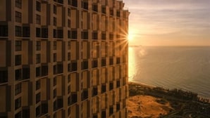 Een hoog gebouw met uitzicht op de ondergaande zon boven de oceaan.