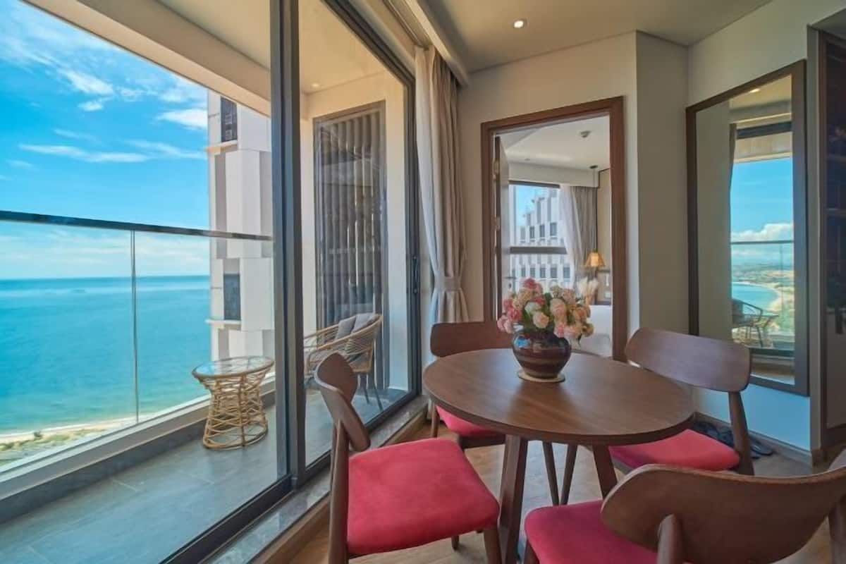 Een balkon met uitzicht op de oceaan, een ronde houten tafel met stoelen en een bloevas.