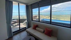 Ein modernes Hotelzimmer mit einer großen Schiebeglastür, die auf einen Balkon mit Blick auf einen Pool führt.