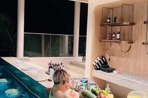 A poolside area with a bar and a wooden cabinet with bottles. - Mandala Couple Horizon Retreat (Phan Thiet)