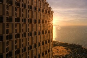 Een hoog gebouw met uitzicht op de oceaan bij zonsondergang.