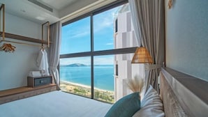 Een hotelkamer met een groot raam met uitzicht op zee en een eiland in de verte.