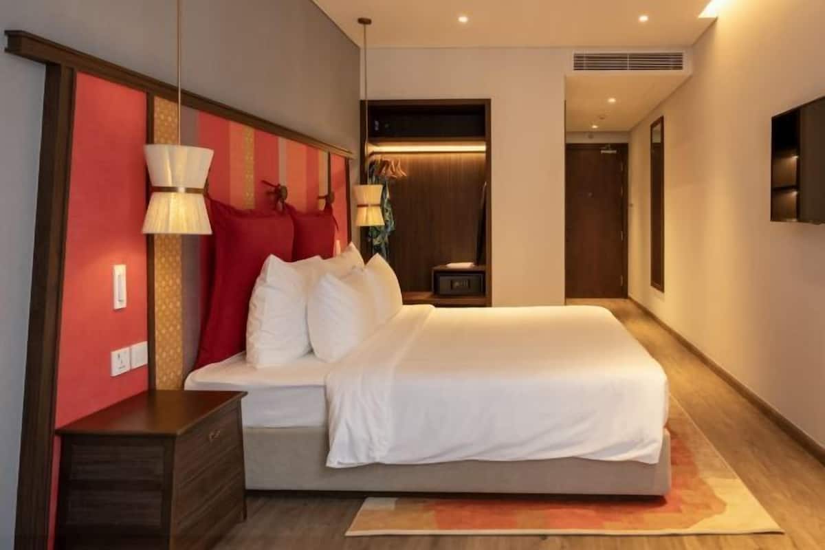 Een moderne hotelkamer met een groot bed, bedlampen, een televisie en een kledingkast.