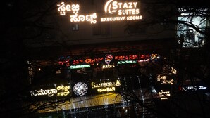 A building with illuminated signs for "Stazy Suites Executive Rooms" and "Sandiraa Resto Bar". - Stazy Suites - Kammanhalli (Bengaluru)