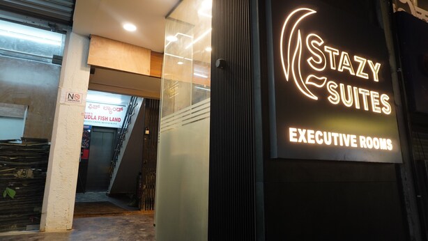 A hotel entrance with a neon sign for 'Stazy Suites' and 'Executive Rooms'. - Stazy Suites - Kammanhalli (Bengaluru)