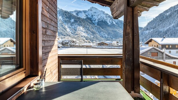 A wooden balcony with a view of snow-covered mountains and buildings. - Apartment 'Gaichtspitze - 8' with Mountain View, Private Balcony and Wi-Fi (Nesselwängle)
