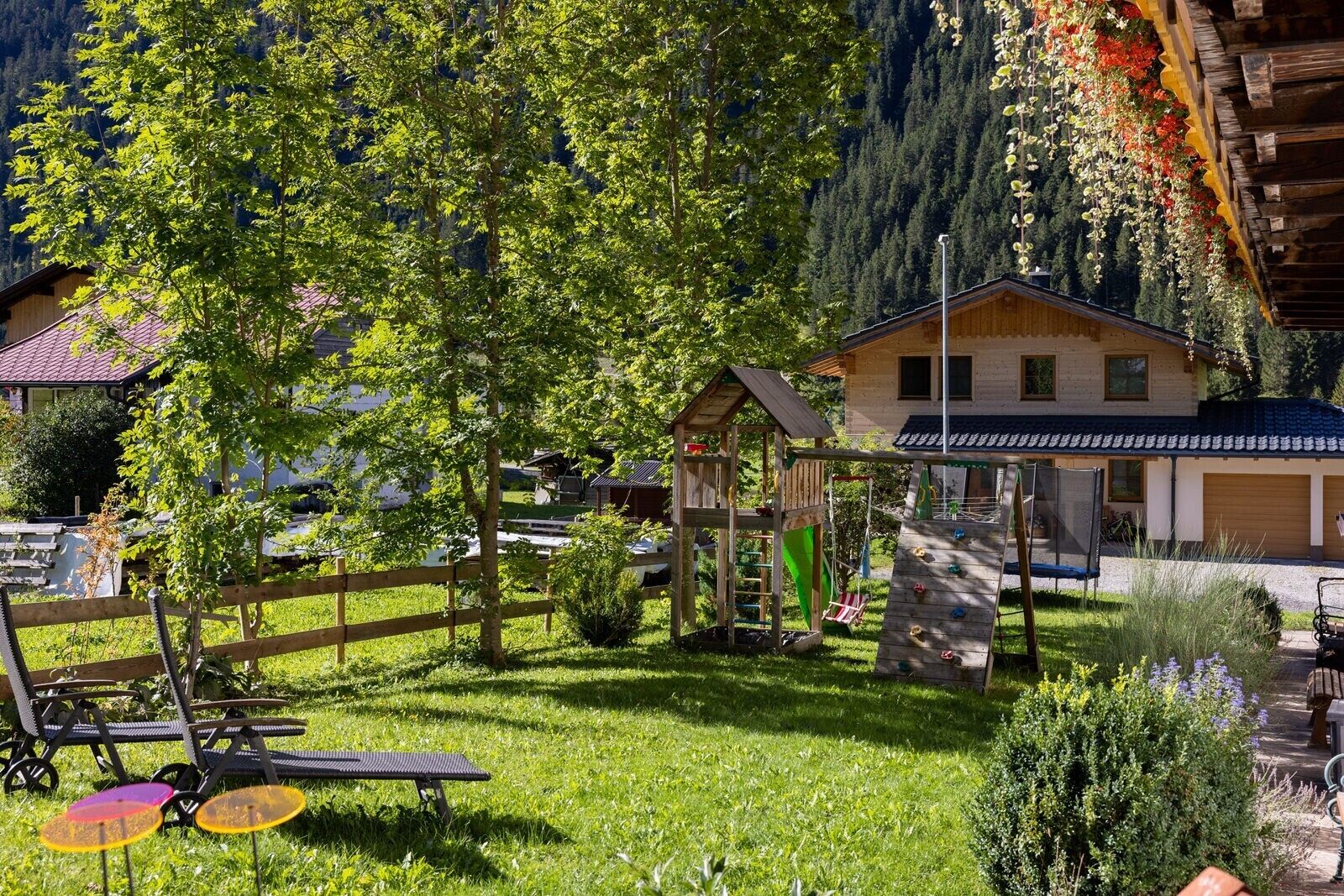 Eine Holzhütte mit Spielbereich, umgeben von üppigem Grün und einem Bergpanorama.