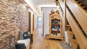 A wooden staircase with a decorative railing, a bookshelf with various items, and a wall with a wooden plank pattern. - Apartment 'Gaichtspitze - 8' with Mountain View, Private Balcony and Wi-Fi (Nesselwängle)