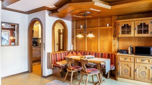 A wooden kitchen with a built-in bench, a dining table, and a microwave. - Apartment 'Schneidspitze - 18' with Mountain View, Private Balcony and Wi-Fi (Nesselwängle)