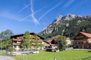 A mountain village with traditional wooden buildings, a clear sky, and a prominent mountain in the background.