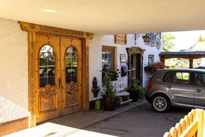Un edificio con un par de puertas de madera, una pequeña tienda y un coche estacionado.