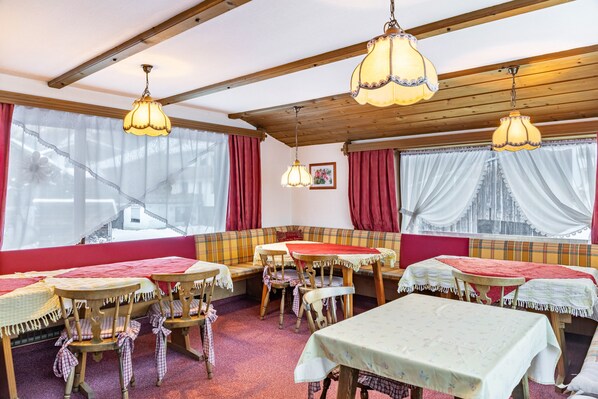 A cozy dining area with wooden tables, benches, and hanging lamps.