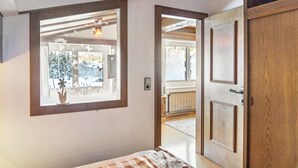 Een slaapkamer met een groot raam, een deur en uitzicht op een eetruimte.