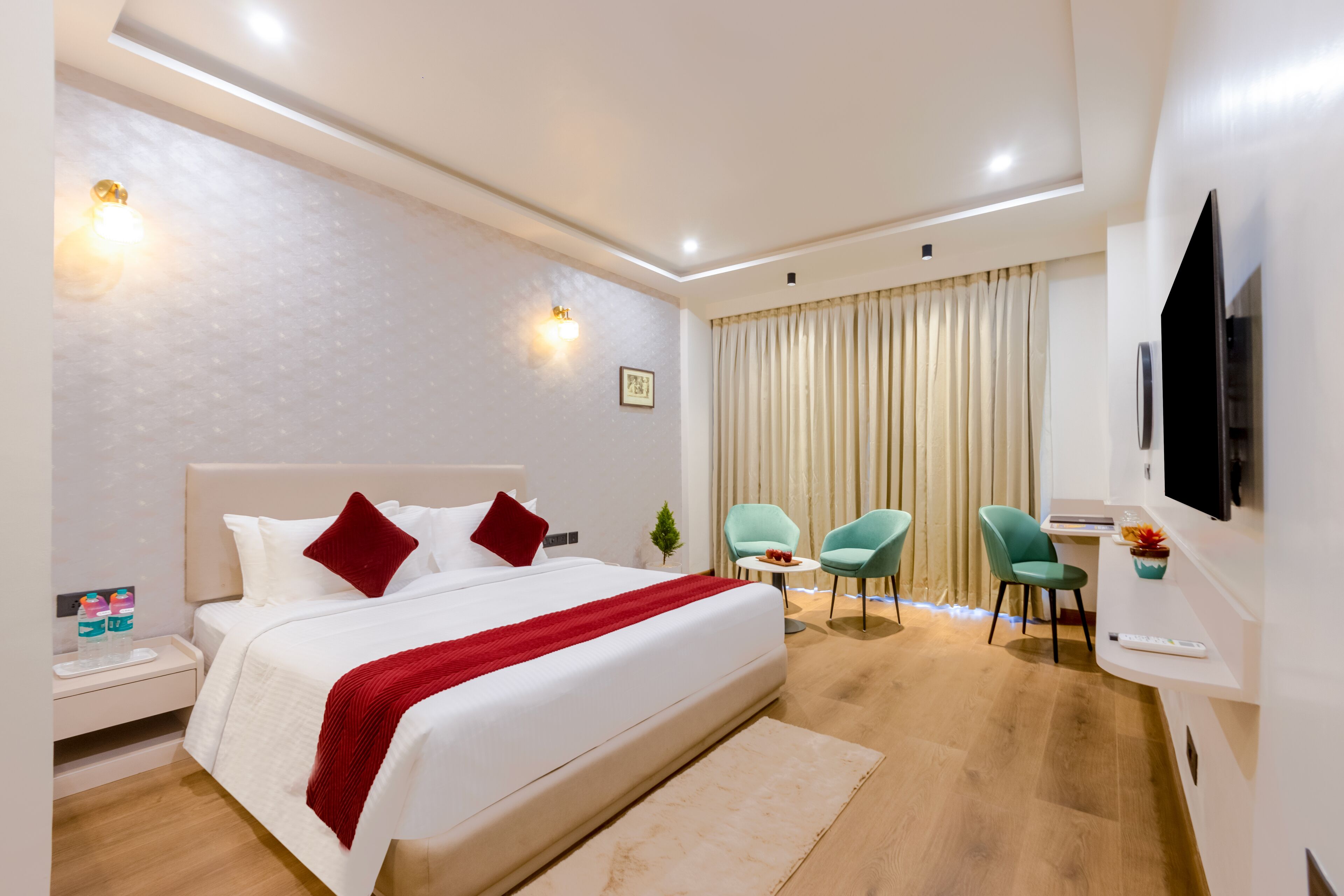 Una habitación de hotel moderna con una cama grande, dos sillones, un televisor y una mesita.