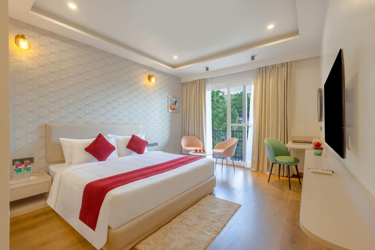 Una habitación de hotel moderna con una cama grande, un escritorio y un balcón con sillas.
