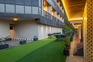 Un patio con césped artificial, mobiliario exterior y fachada de edificio moderna con un muro con diseño.