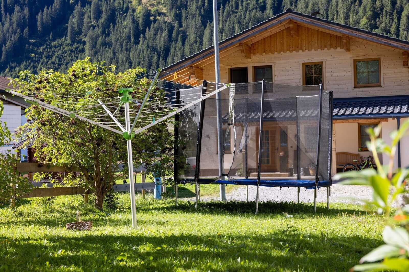 A wooden house with a balcony, a clothesline, and a trampoline in the yard.