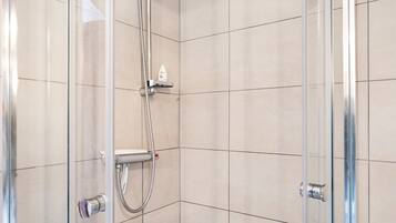 Een douchecabine van glas met een handdouche en een bedieningspaneel aan de muur.