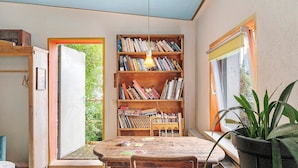 A cozy reading nook with a wooden bookshelf, a table, and chairs, and a potted plant.