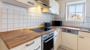 Une cuisine moderne avec des armoires blanches, un plan de travail en bois, un four encastré et un lave-vaisselle.