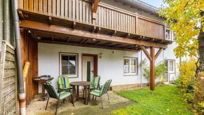 Une terrasse en bois avec une table et des chaises, un patio couvert et une pelouse.