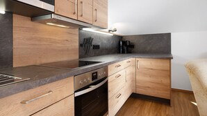 A modern kitchen with wooden cabinets, a stainless steel range hood, and a built-in oven.
