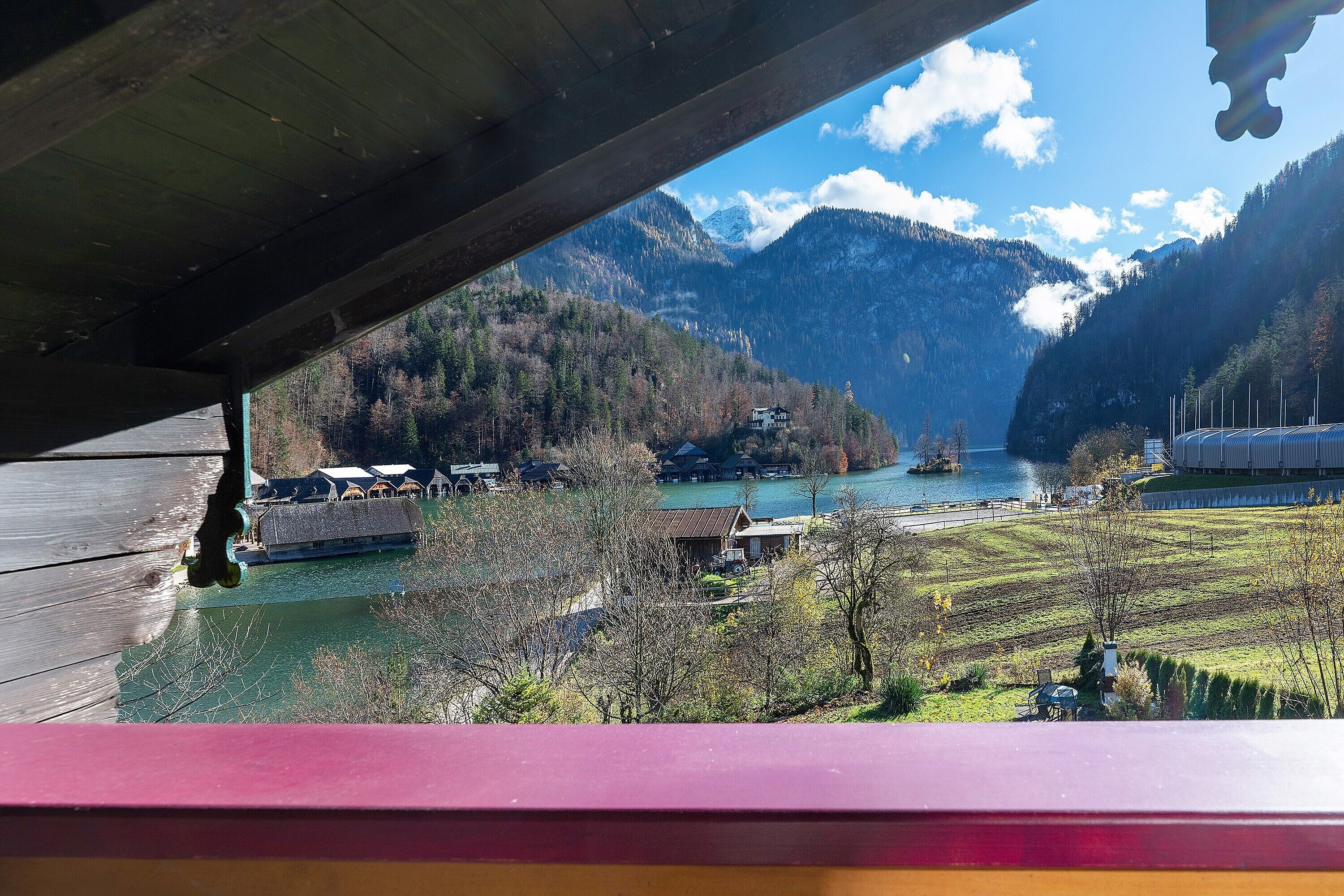 Une vue sur un paysage montagneux avec un lac, des bâtiments et un quai.