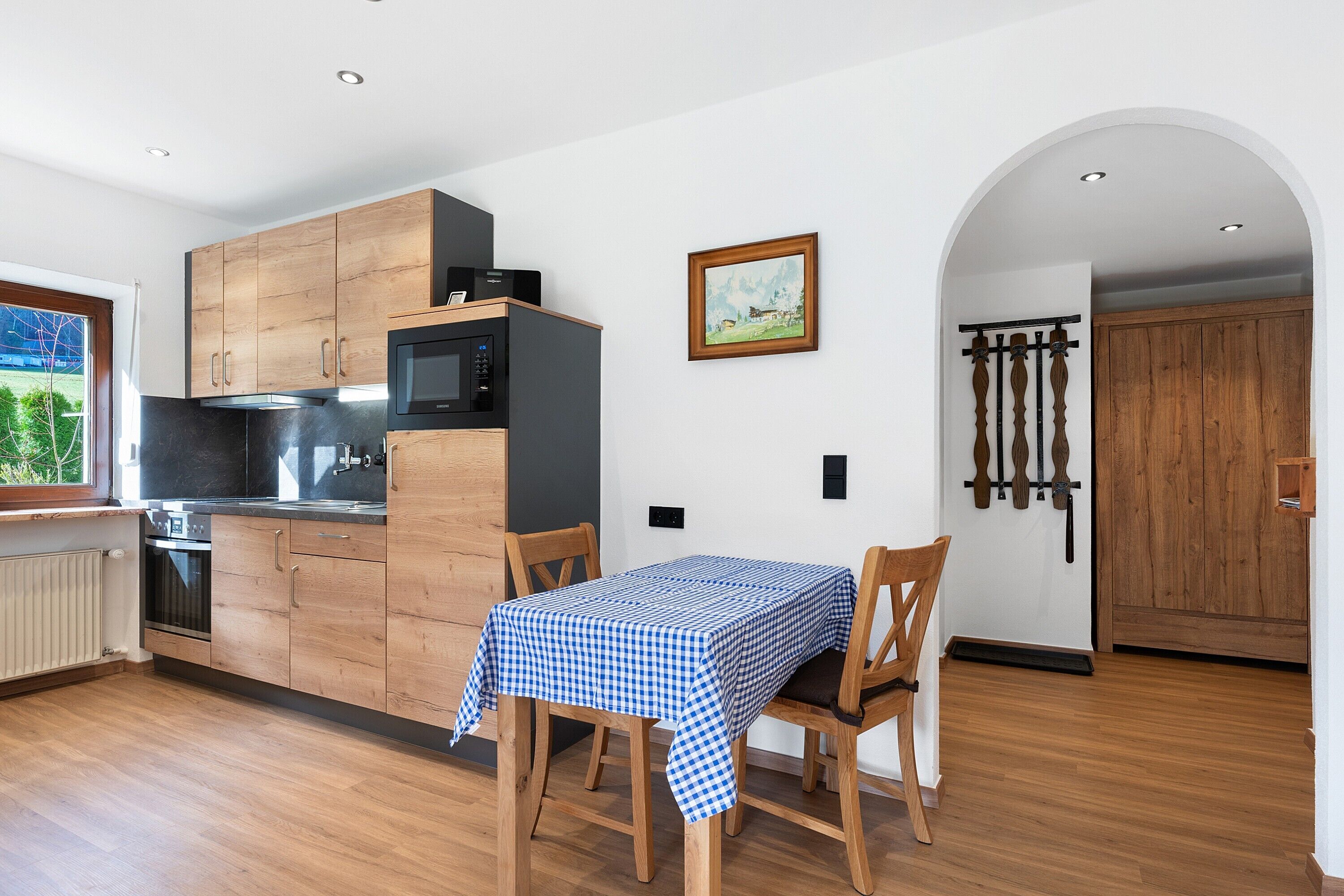 A modern kitchen with wooden cabinets, a microwave, and a dining table with chairs.