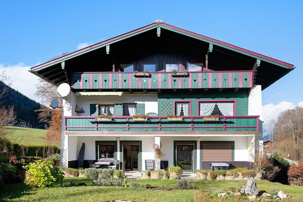 Eine zweistöckige Chalet mit Balkon, Satellitenschüssel und einem gepflegten Garten.