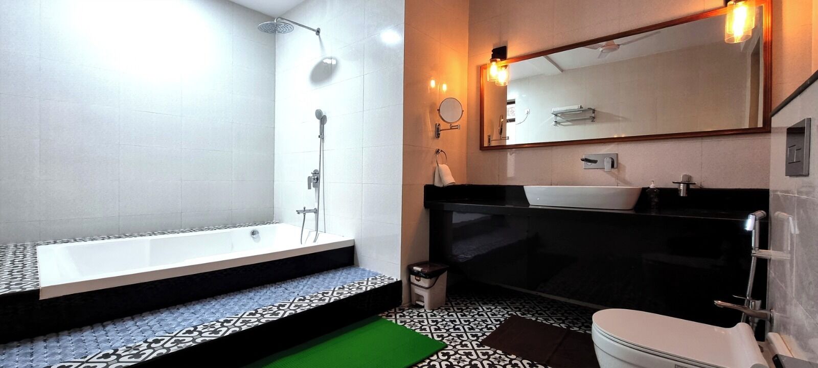 A modern bathroom with a bathtub, a large mirror, and a black sink.