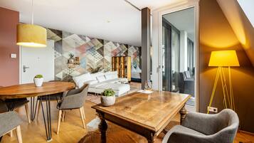 Ein modernes Wohnzimmer mit einem Holzessttisch, grauen Stühlen, einem weißen Sofa und einer strukturierten Wand.