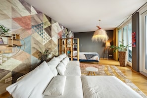 A modern living room with a geometric-patterned wall, a sofa, a small round table, and a floor lamp.