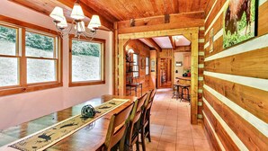 A wooden interior with a dining area, a kitchen, and a view of the outdoors.