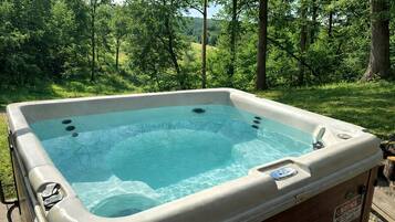 Een hottub in een natuurlijke omgeving, met een houten terras en een veiligheidsbericht.