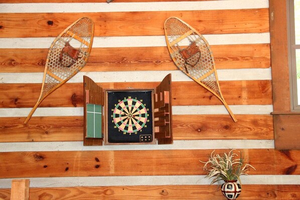Une cible de fléchettes fixée à un mur en bois, avec deux paniers décoratifs de chaque côté.