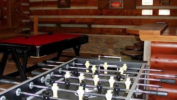 Una stanza con tavola da calcio, tavola da biliardo e angolo bar.