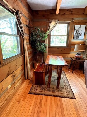L’intérieur d’un chalet en bois, avec une table à manger, des chaises, une plante en pot et une lampe.